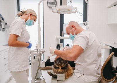 Zubný lekár a asistentka pri estetickom stomatologickom ošetrení pacienta